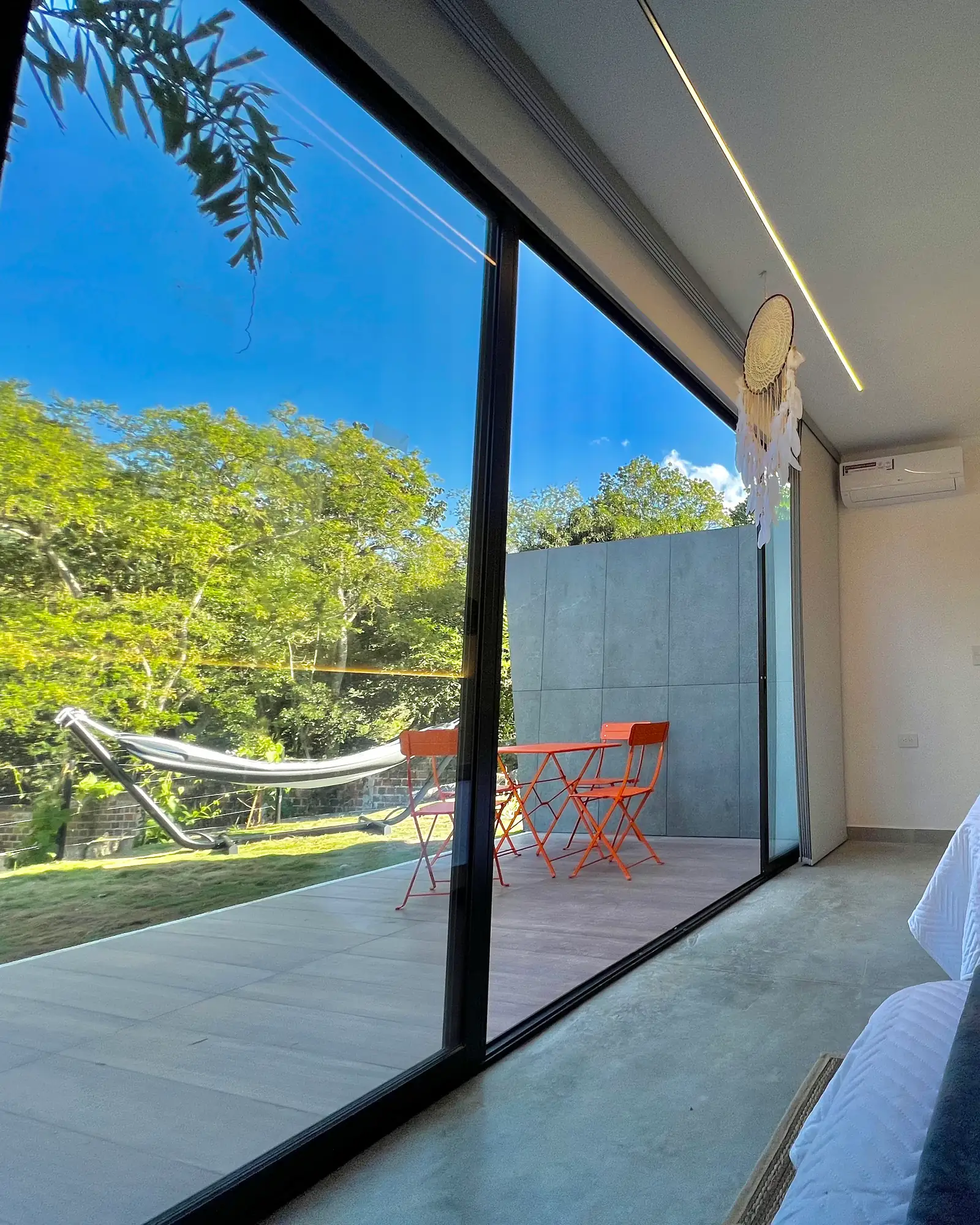 Pared de vidrio del Glamping Familiar que deja ver la hamaca y el verde de afuera
